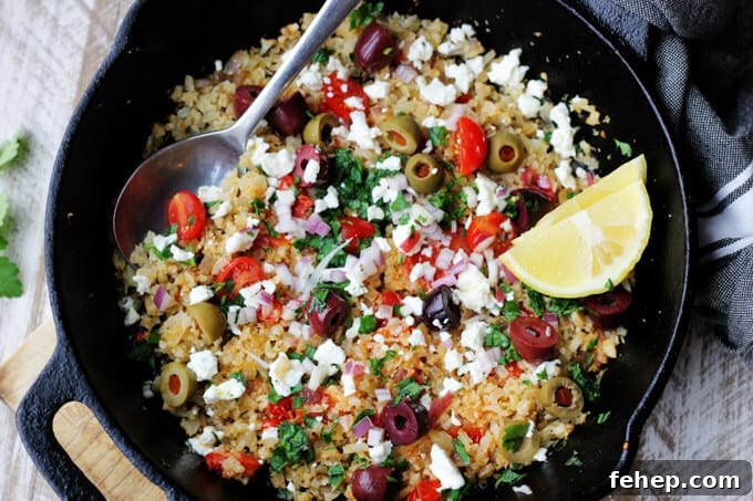Fried riced cauliflower with Mediterranean twist in a skillet with spoon and lemon