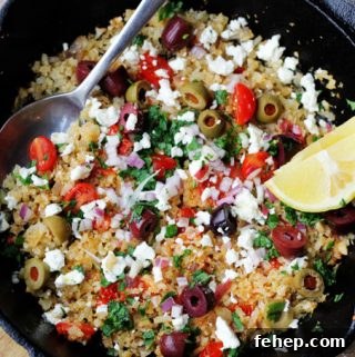 Fried riced cauliflower with Mediterranean twist in a skillet with spoon and lemon