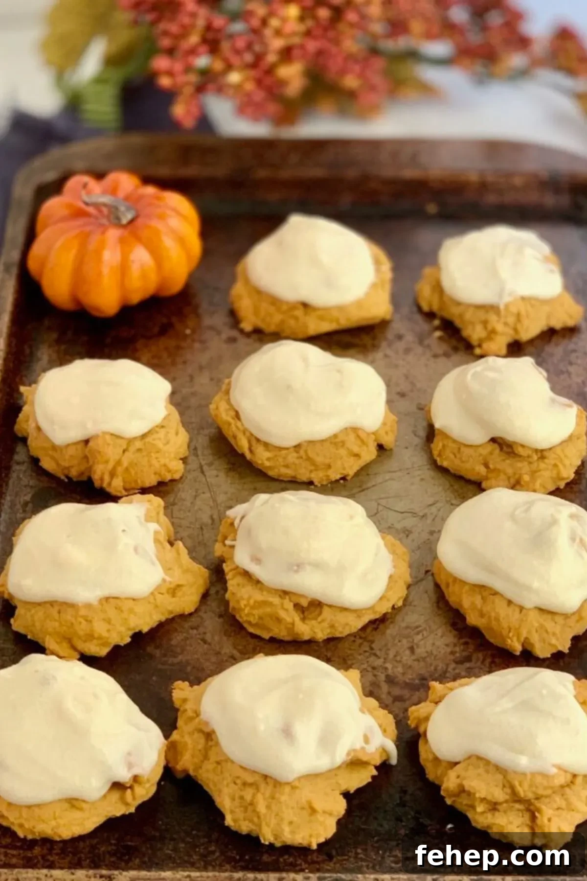 A baking sheet with frosted pumpkin cookies.