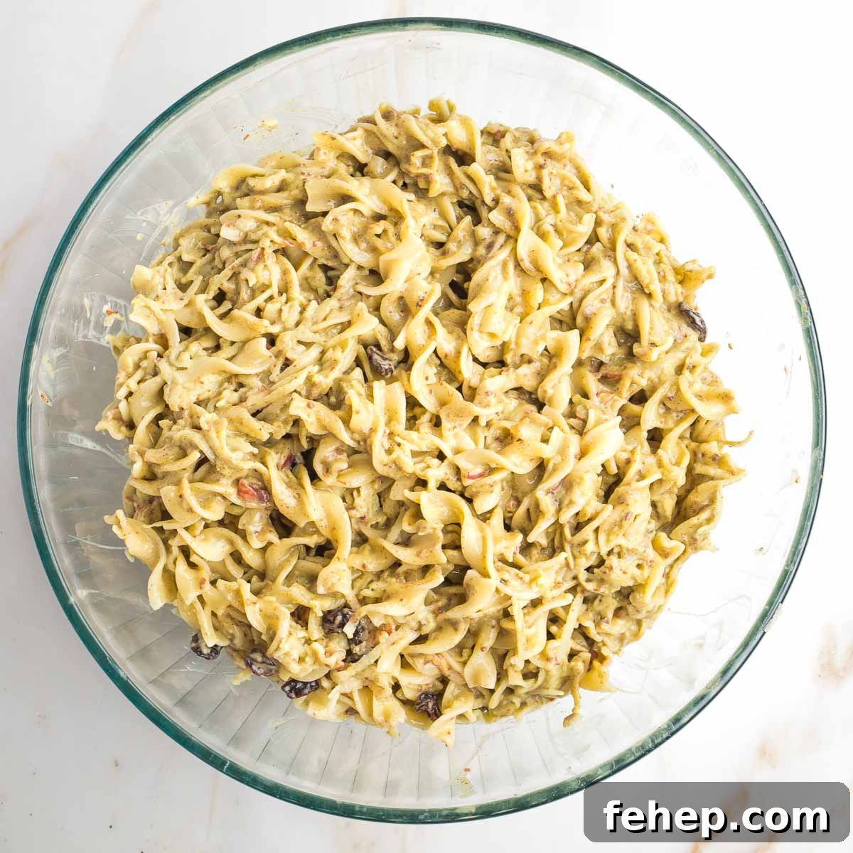 Large glass mixing bowl with noodle pudding mixture.