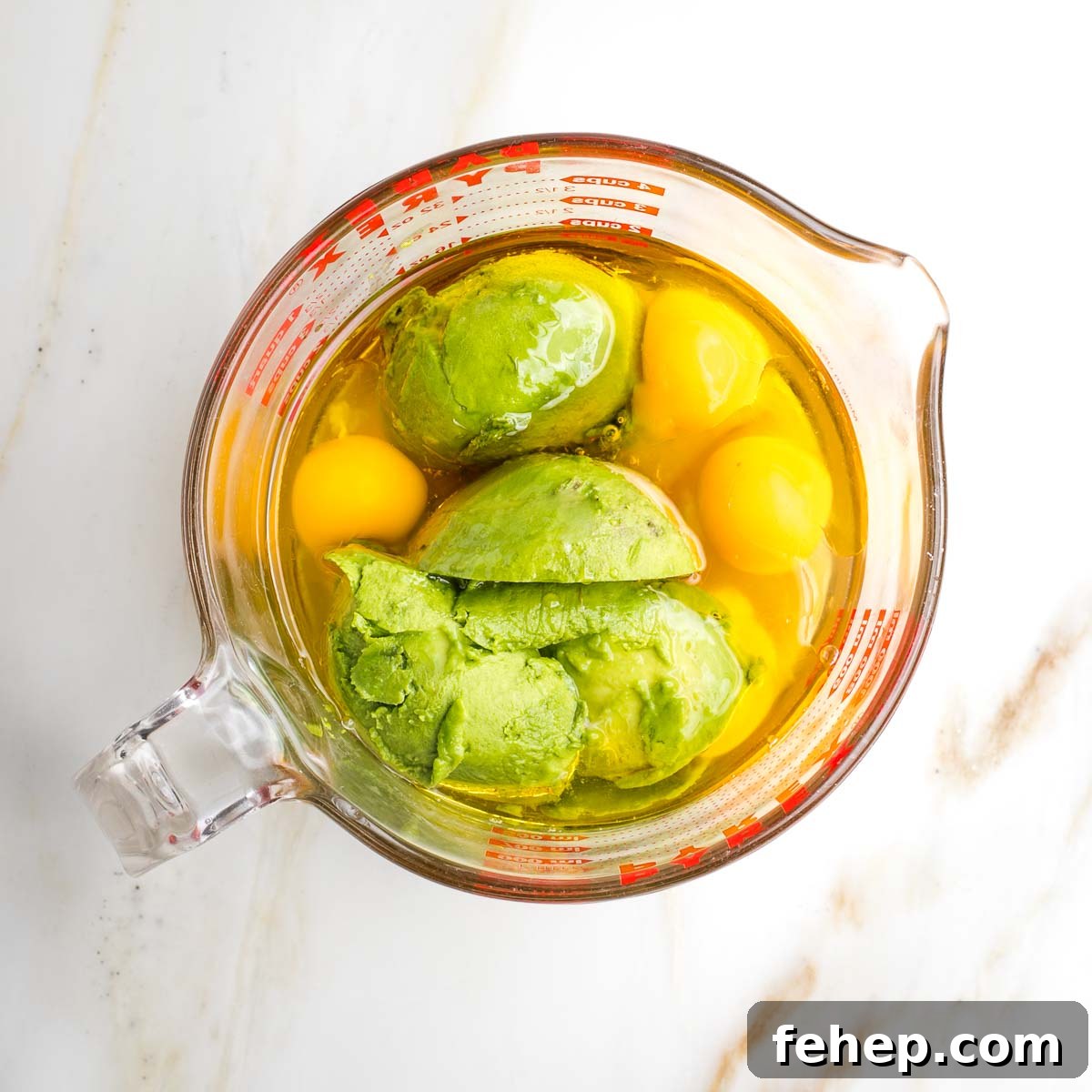 Whole eggs, avocado, oil and honey in a large measuring cup.