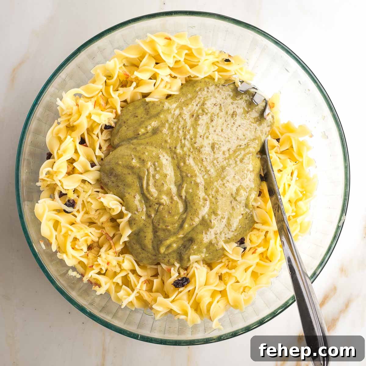 Large mixing bowl with noodles and brownish pudding being mixed in.