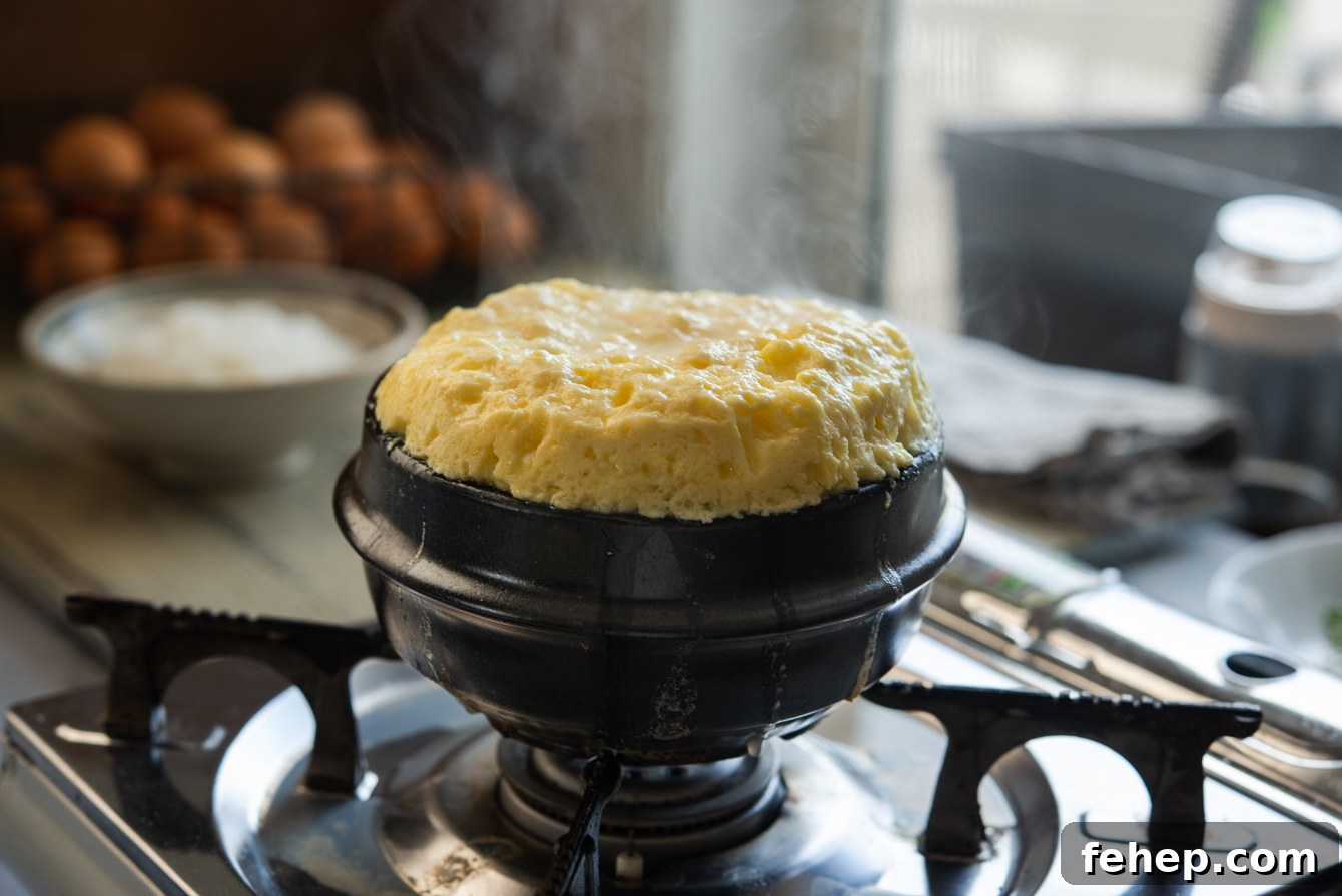 Fluffy gyeran jjim puffed up like a volcano with steam rising above the rim of the ttukbaegi.