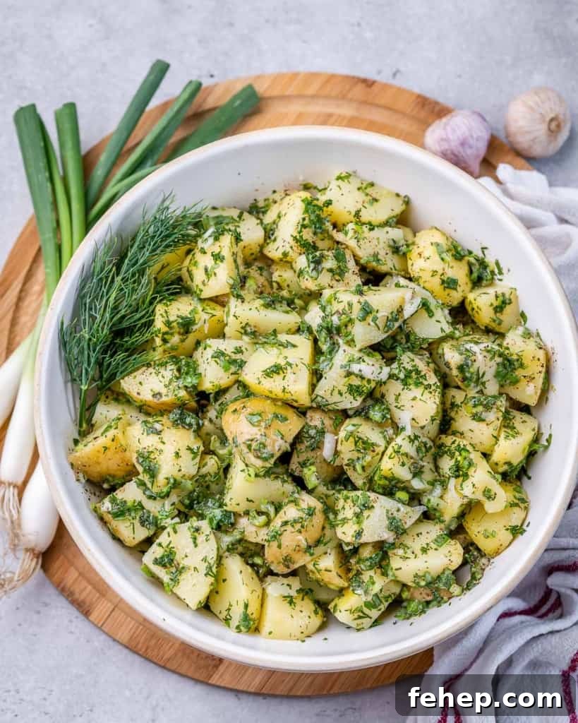Classic Herbed Potato Salad with Fresh Dill and Chives 2 Top view of potato salad with green herbs in a white round bowl.