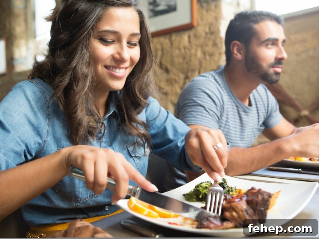 A man and a woman eating a plate of food at a restaurant.