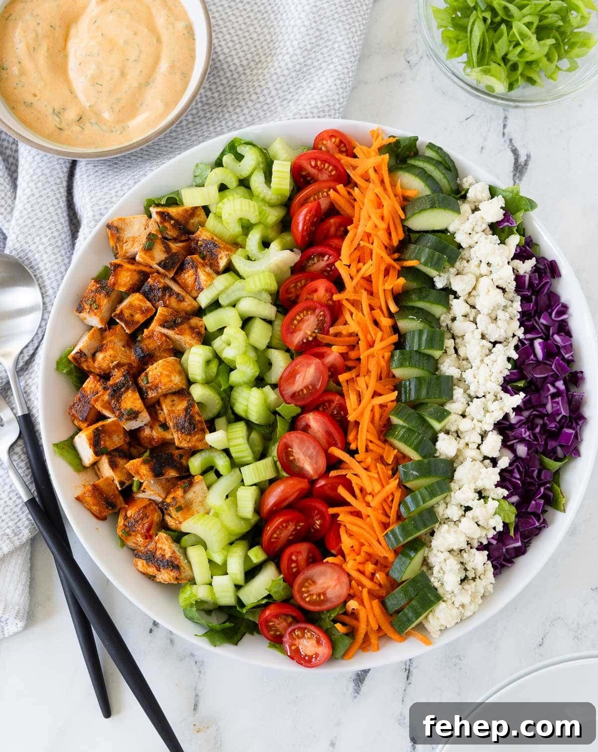 Spicy Buffalo Chicken Salad Recipe with Creamy Ranch Dressing 2 Buffalo chicken salad arranged in colorful rows, with chicken, tomatoes, celery, blue cheese, and carrots.