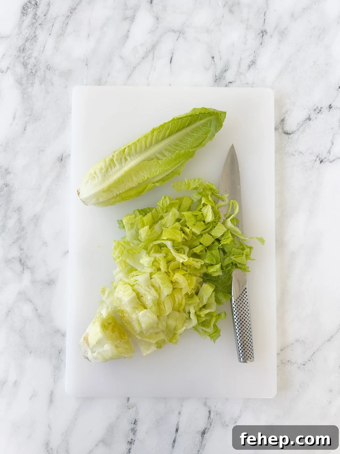 Spicy Buffalo Chicken Salad Recipe with Creamy Ranch Dressing 6 Chopping hearts of Romaine lettuce on a cutting board with a chef's knife.