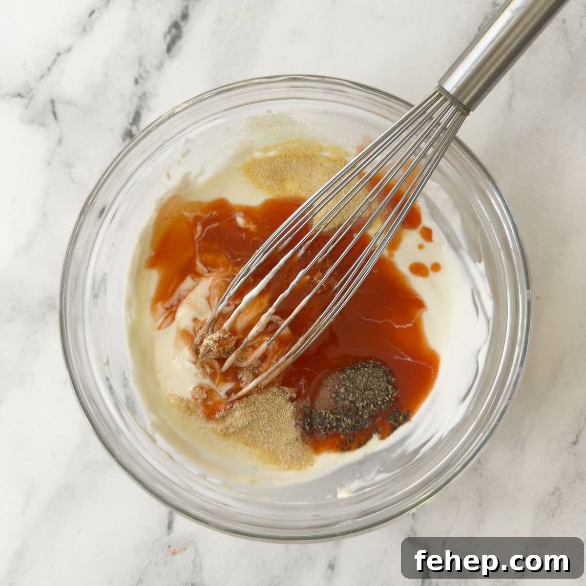 Spicy Buffalo Chicken Salad Recipe with Creamy Ranch Dressing 8 Blending ingredients for buffalo ranch dressing in a glass bowl with a whisk.