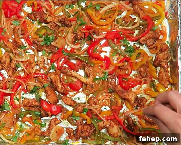 30-Minute Sheet Pan Chicken Fajitas Meal 6 close-up of the flaming-sizzling chicken fajitas on a large sheet pan, being sprinkled with cilantro