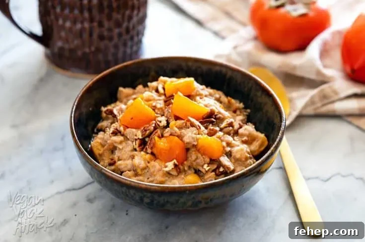 Ceramic bowl filled with persimmon oatmeal, and golden spoon, with a cup of coffee