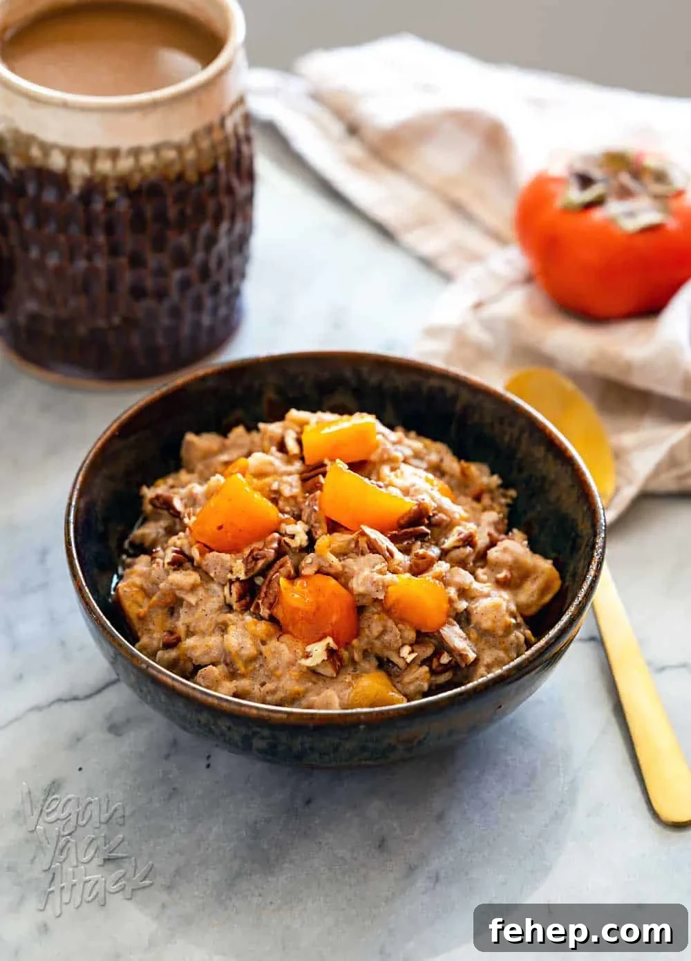 Ceramic bowl filled with persimmon oatmeal, and golden spoon, with a cup of coffee