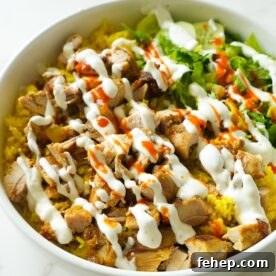 Halal cart chicken over rice with creamy white sauce, lettuce, and a dash of hot sauce.