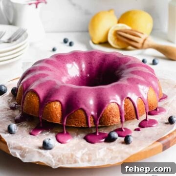 A straight on shot of lemon pound cake with blueberry glaze dripping over the edges of the cake
