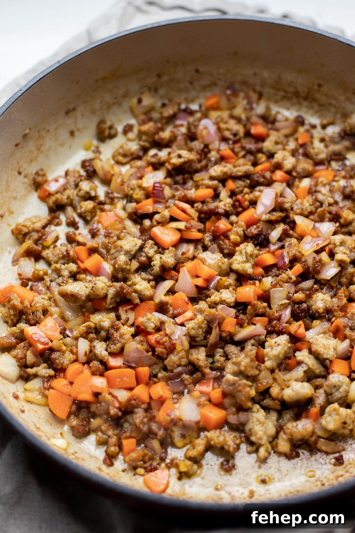 Cooked sausage and carrots in a pan.