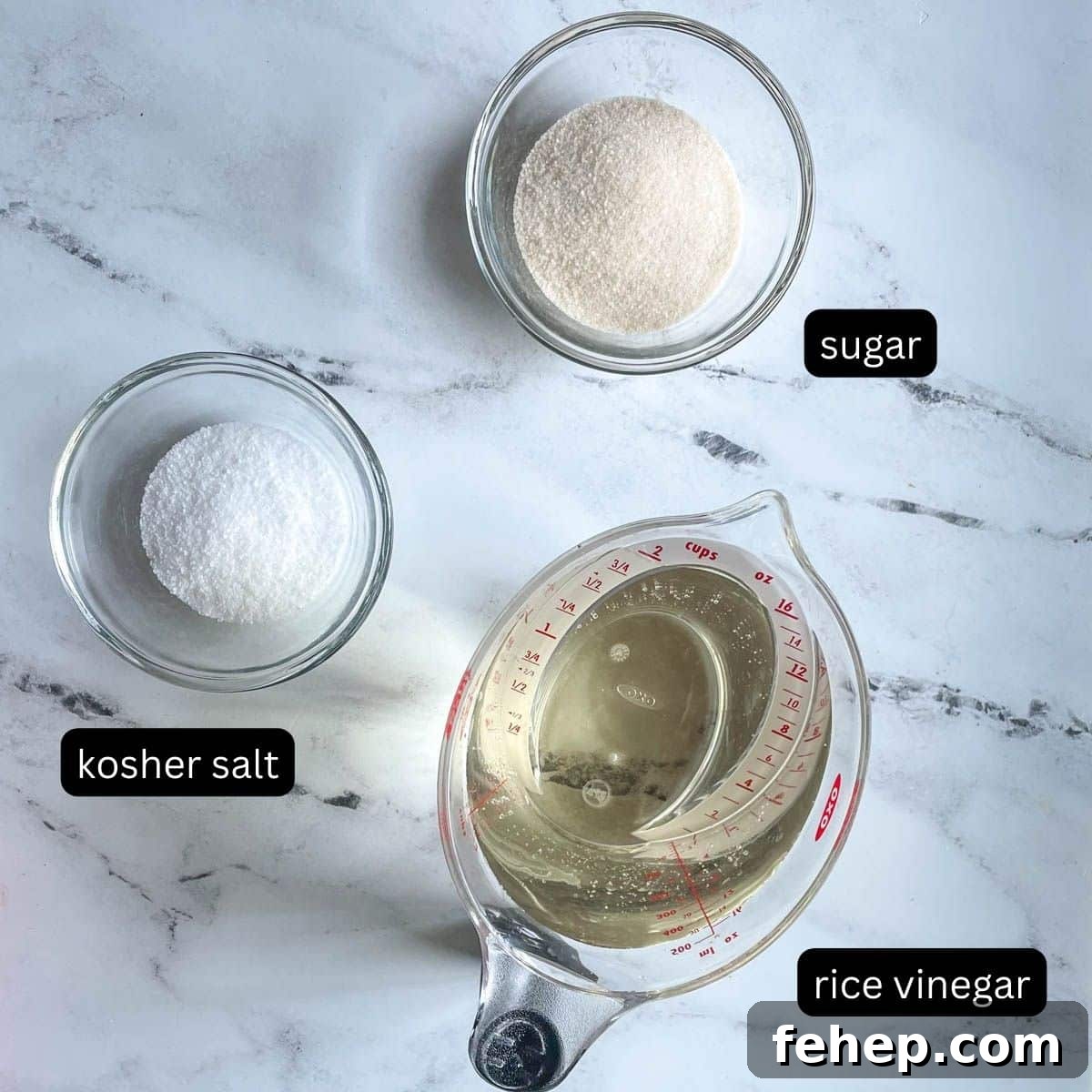 Kosher salt, sugar, and rice vinegar are shown on a white marble counter.