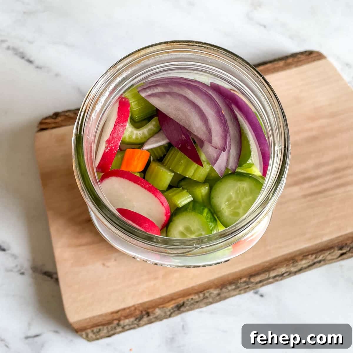 Mixed, cut vegetables are shown in a glass jar.