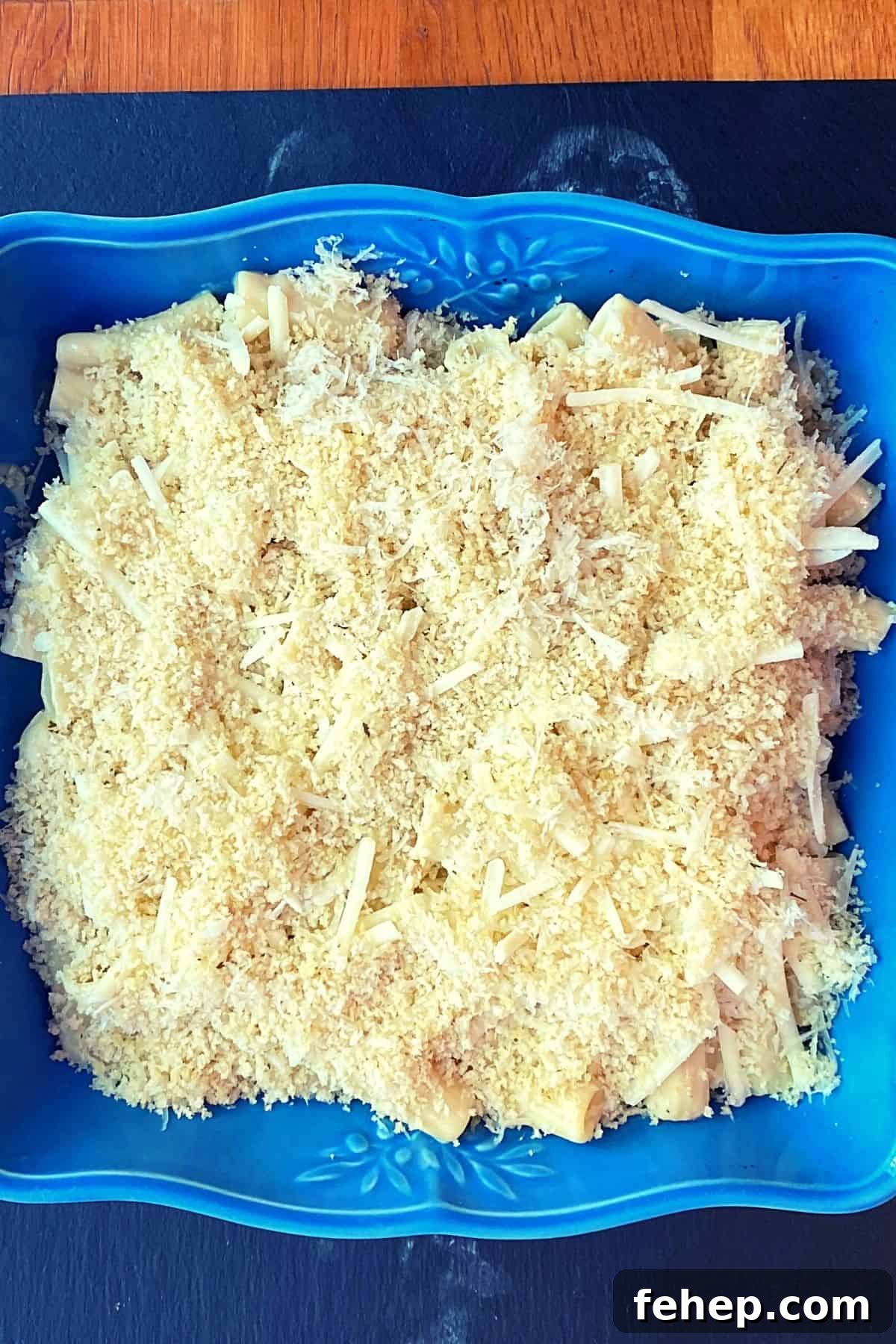 Overhead view of bread crumb and cheese sprinkled over pasta before baking