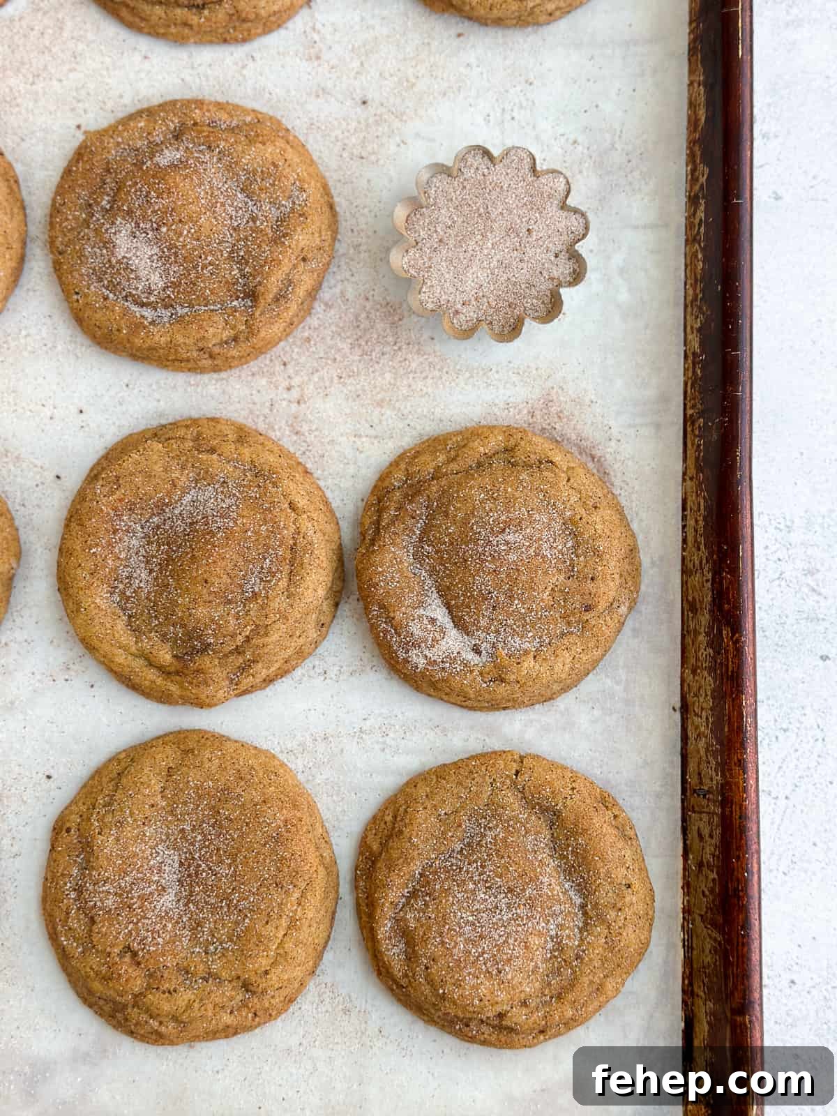 pumpkin cheesecake cookies lined up with a little bowl of cinnamon sugar.