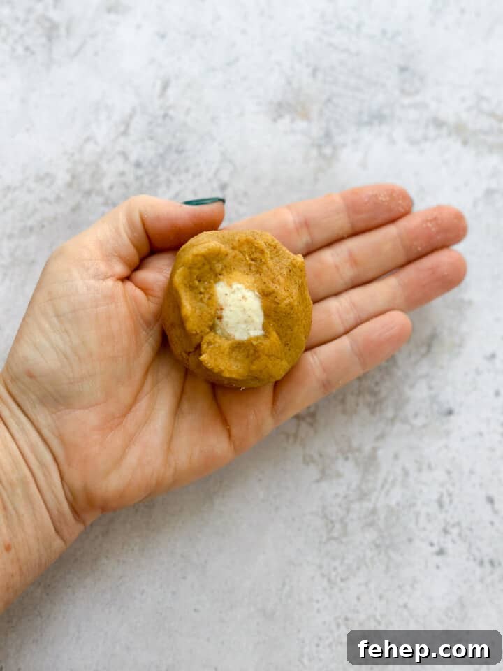 hand showing how the cheesecake is filled in the cookie dough.