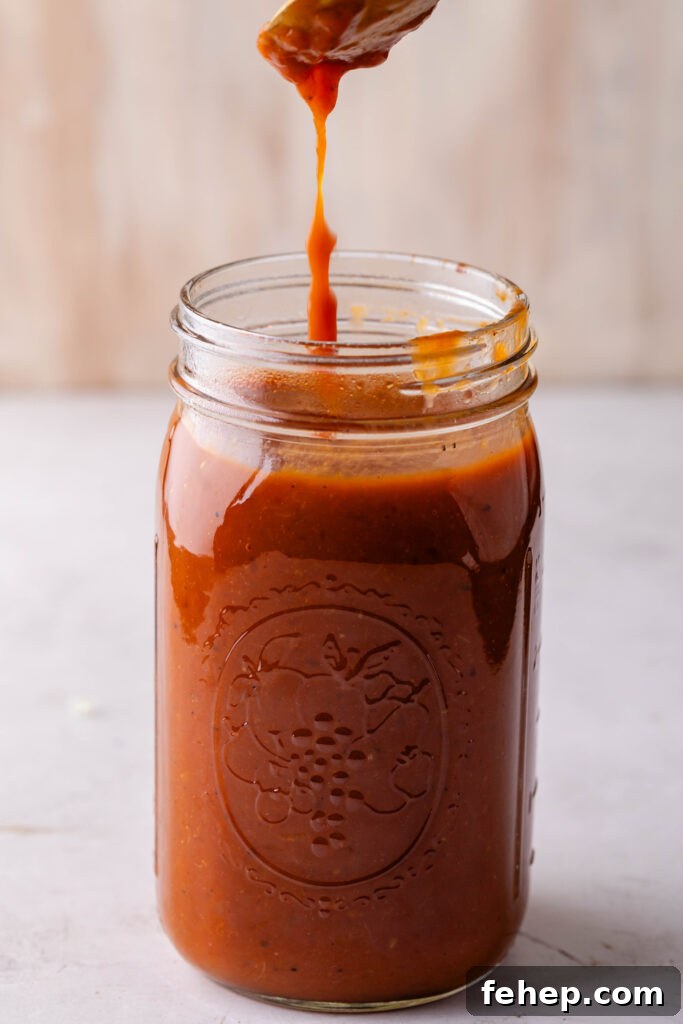 gold spoon dripping peach bbq sauce into a jar of sauce