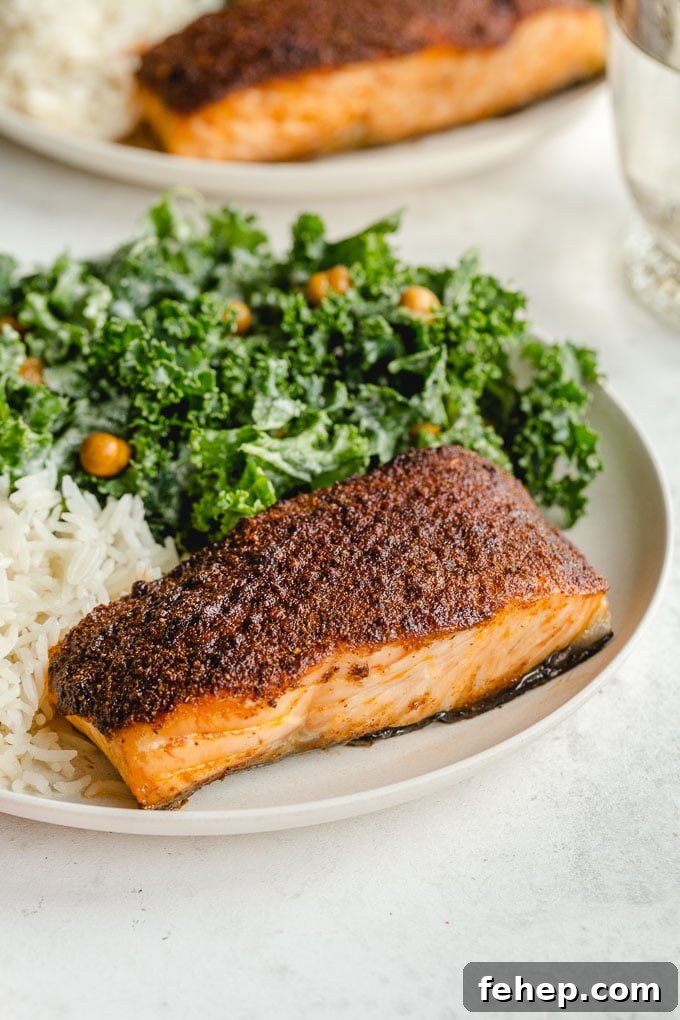 Side view of a crispy air fried salmon fillet on a plate with rice and kale.