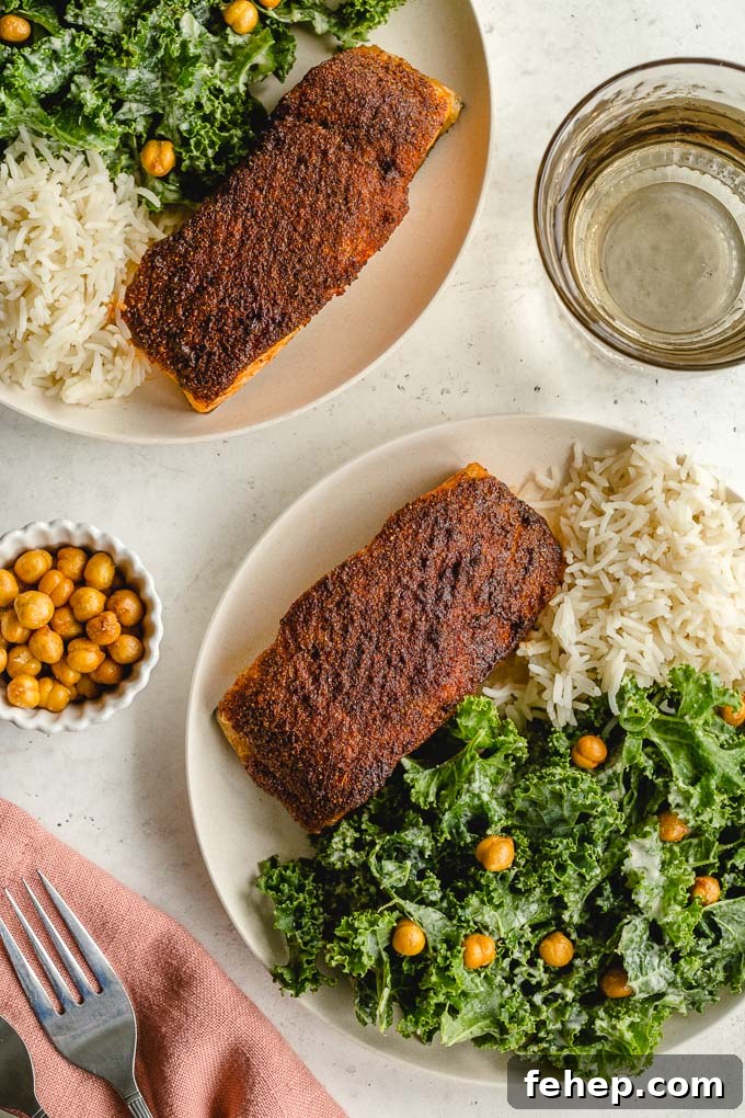 Overhead view of air fryer salmon fillets on two plates along with kale and rice.