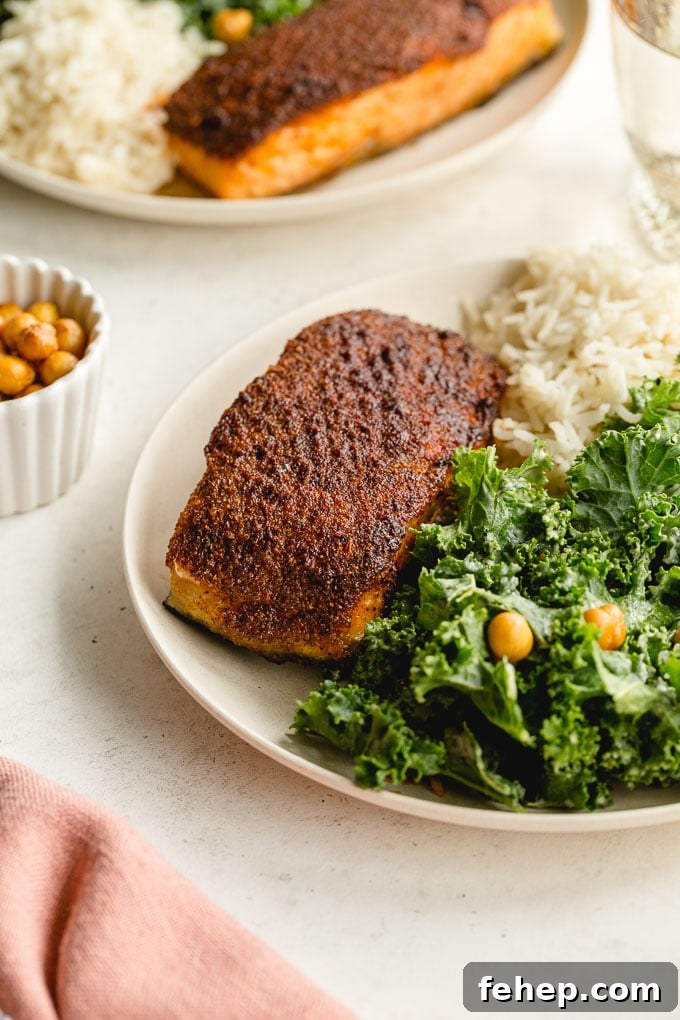 Up close view of crispy air fryer salmon on a plate with kale and rice.