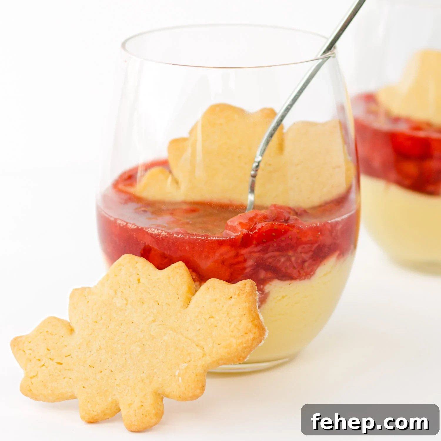 Maple custard with strawberry compote in a dessert glass with maple leaf shaped sugar cookie.