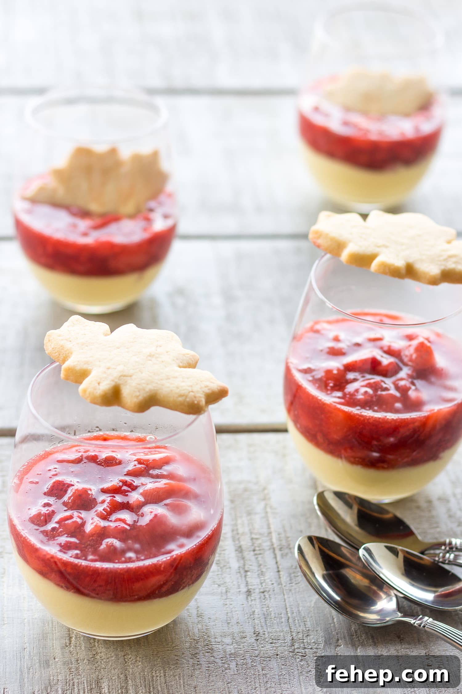 4 glasses of maple custard with strawberry compote topped with a maple leaf shaped sugar cookie