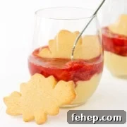 Maple custard with strawberry compote in a dessert glass with maple leaf shaped sugar cookie.