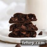 three gluten-free chocolate chocolate chip cookies stacked on a white plate