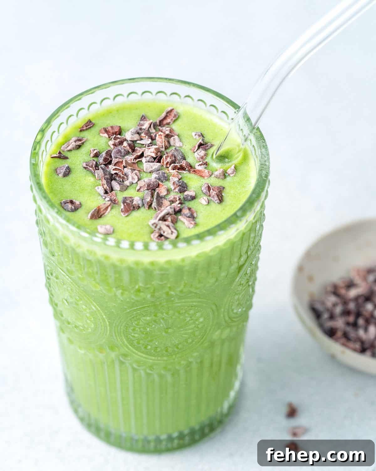 a cup filled with green shamrock protein smoothie topped with cocoa nibs.