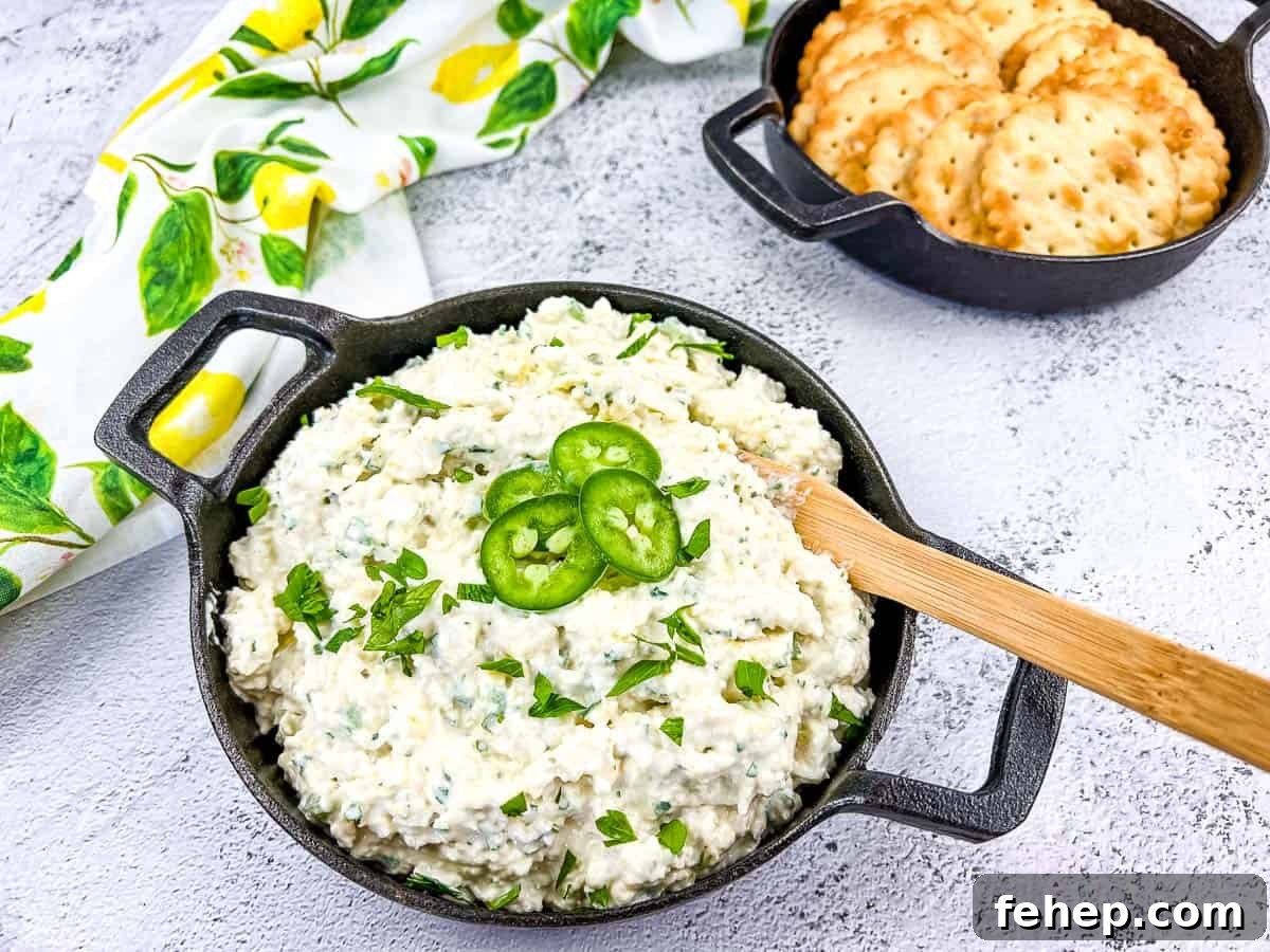 Artichoke Jalapeno Dip in a black bowl with crackers nearby.