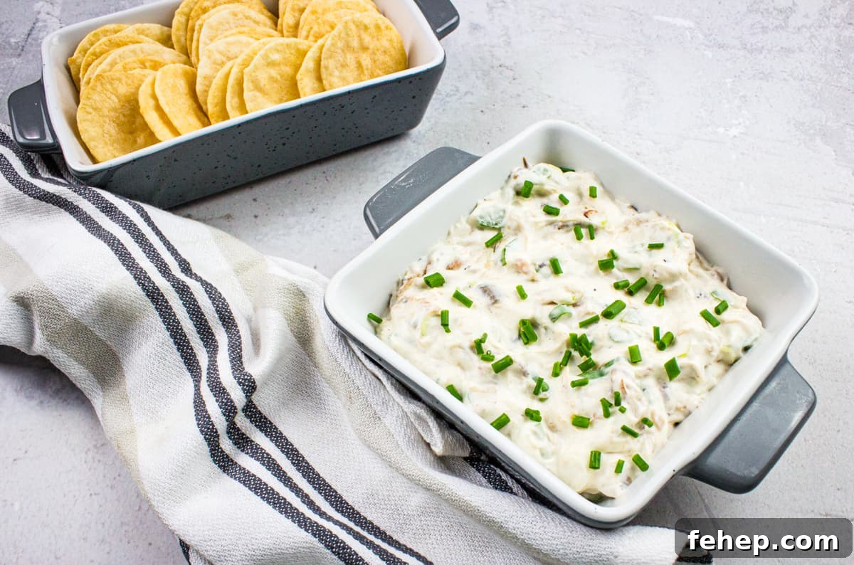 A bowl of cold crab dip with crackers and chives.