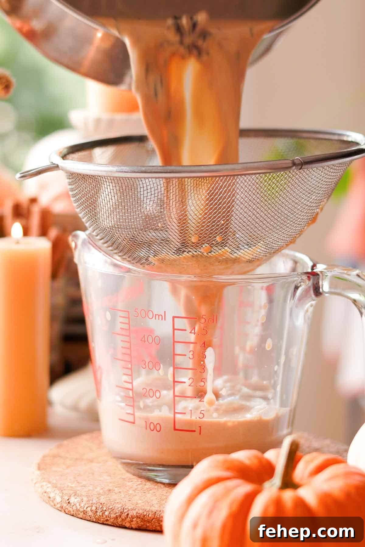 Pumpkin Spice Chai Latte Recipe: Cozy Fall Coffeehouse Drink 7 using metal straining basket to strain pumpkin spice chai latte into glass measuring cup
