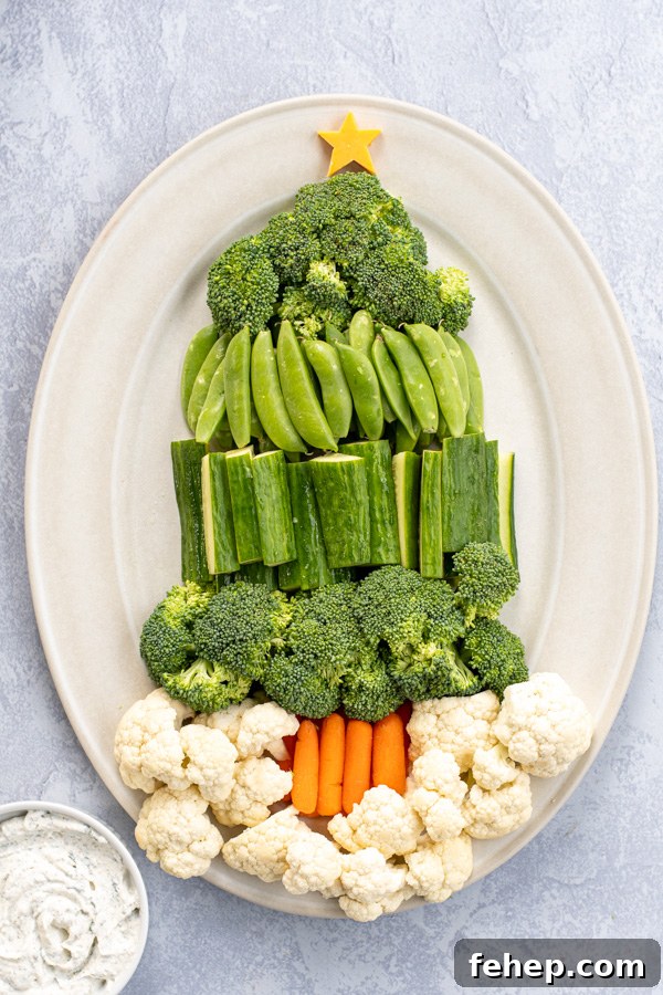 Festive Christmas Tree Vegetable Platter Ideas for Holiday Parties 4 A tray with green vegetables shaped into a Christmas tree with carrot sticks as a base and cauliflower for snow.
