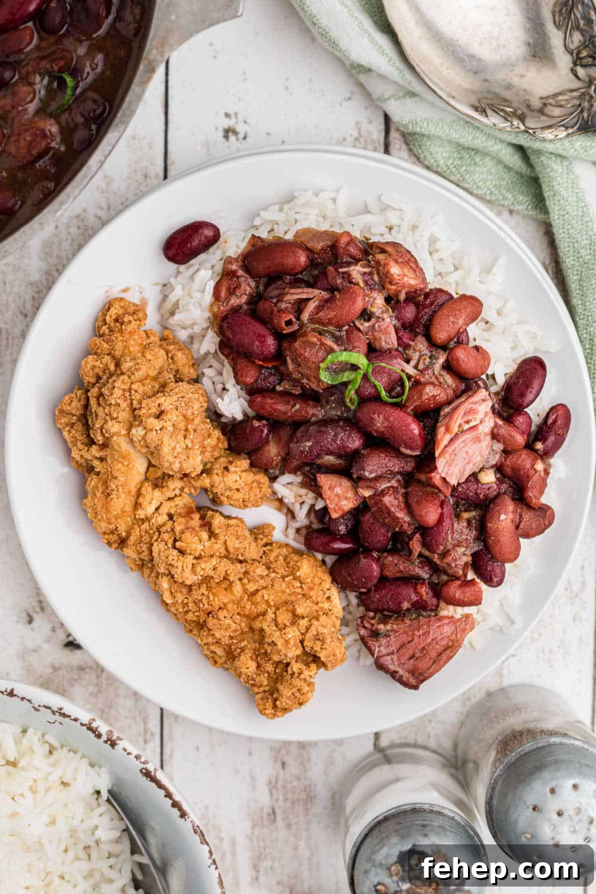 A dished up plate of fried chicken and red beans and rice with ham hocks.