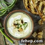 Wondering how to use garlic scapes? A great way to use them is to make a cold garlic scape soup! Perfect for summer and easy to make ahead. Scapes and leeks sauteed in butter and simmered with potatoes make a great twist on the classic French vichyssoise.