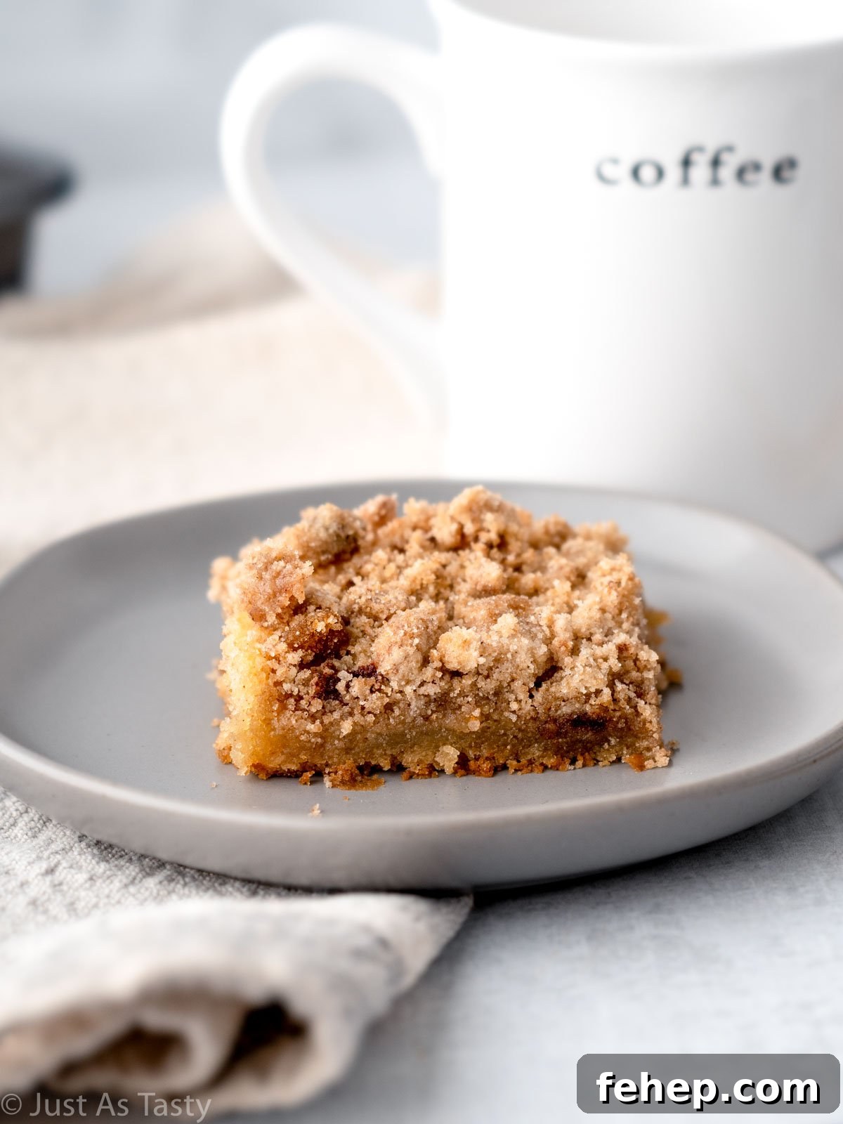 Slice of eggless coffee cake with streusel topping on a grey plate.
