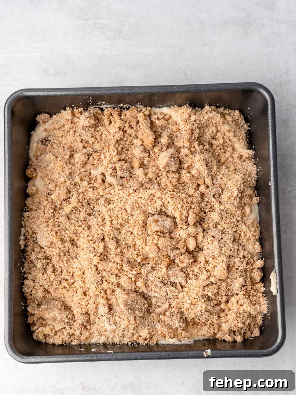Cake batter topped with streusel in a square baking pan.