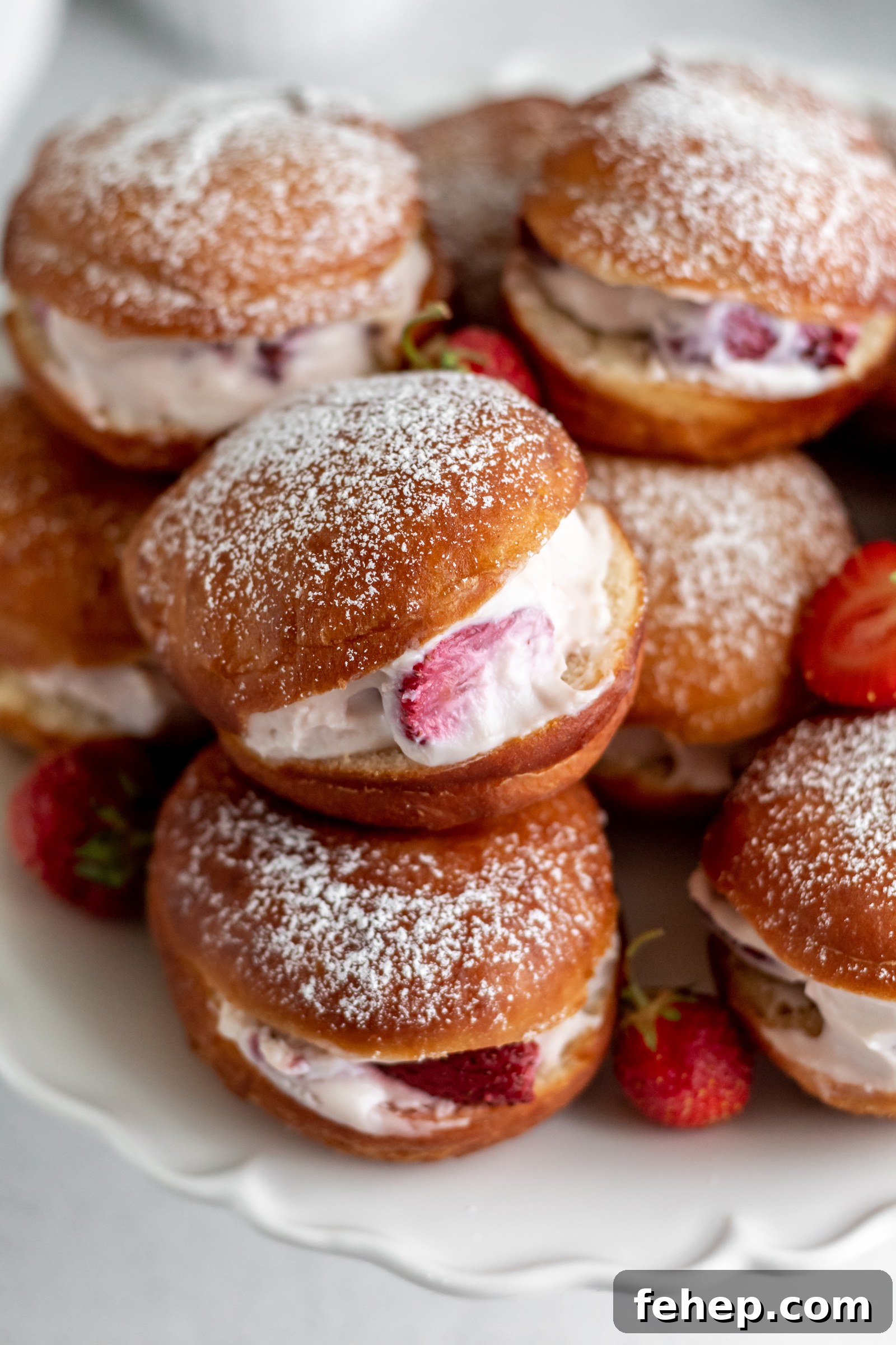 Doughnuts filled with cream and strawberries and dusted with powdered sugar on top.
