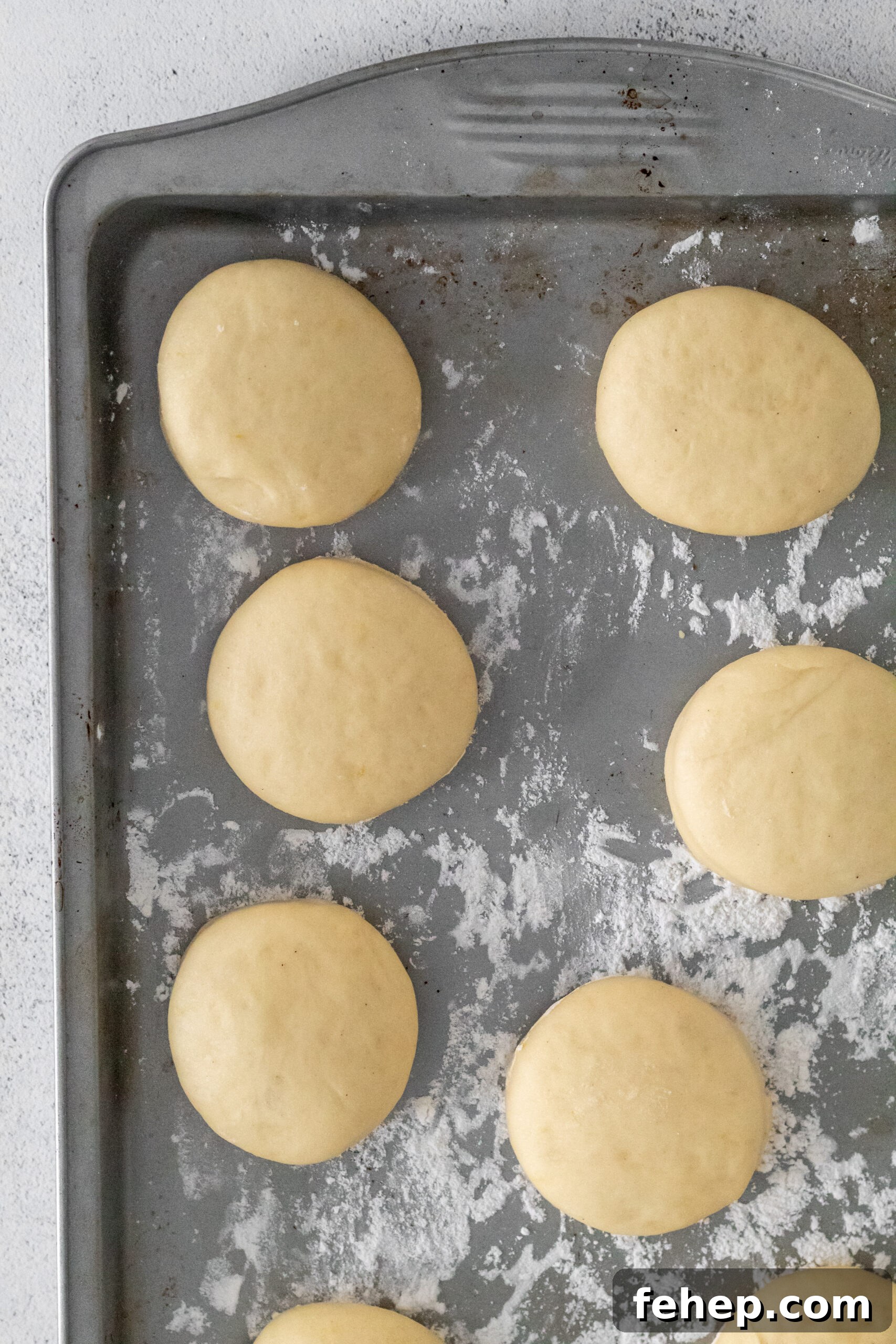 Donut dough formed into balls on a floured baking sheet.