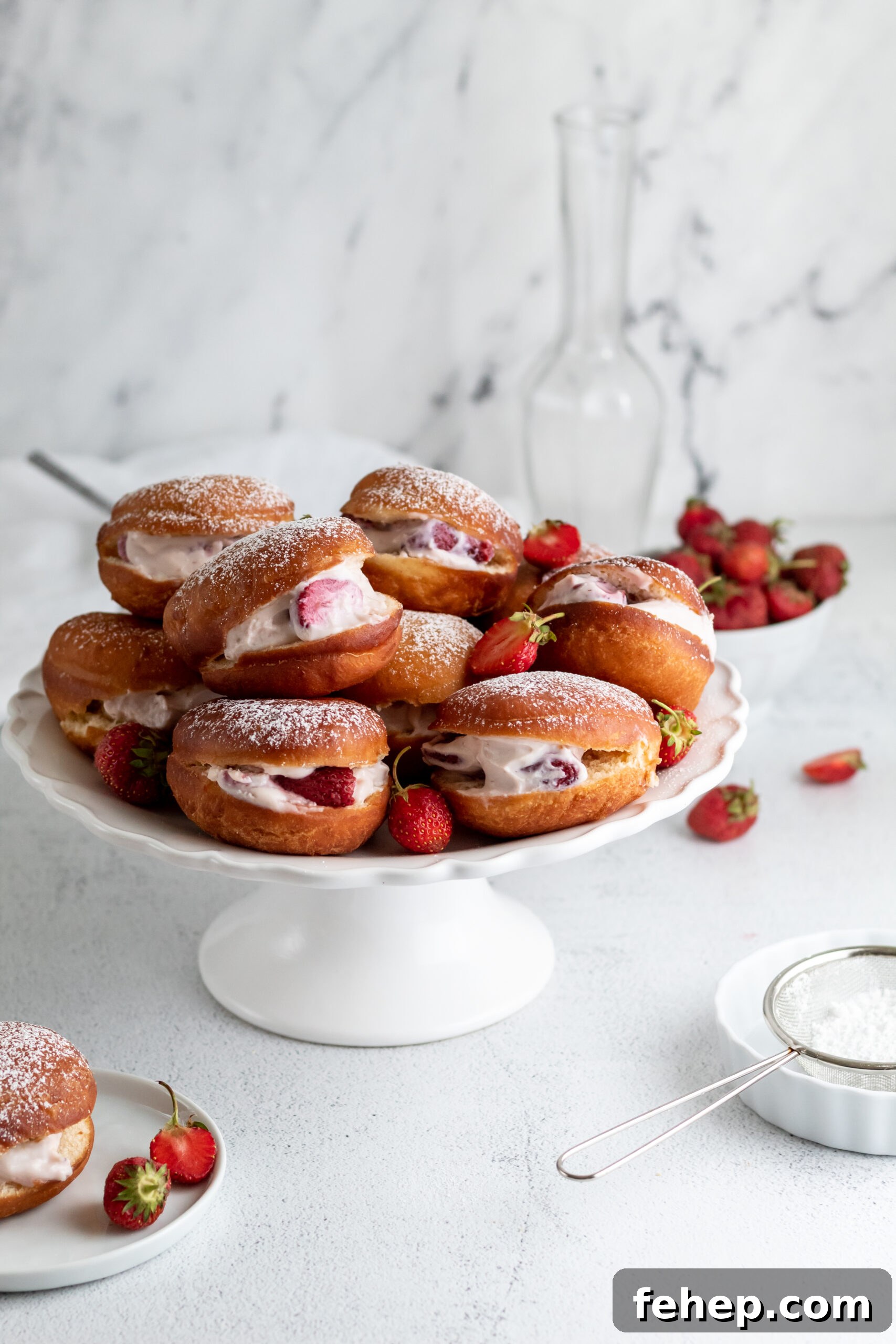 A cake stand topped with a pile of donuts filled with cream and strawberries.
