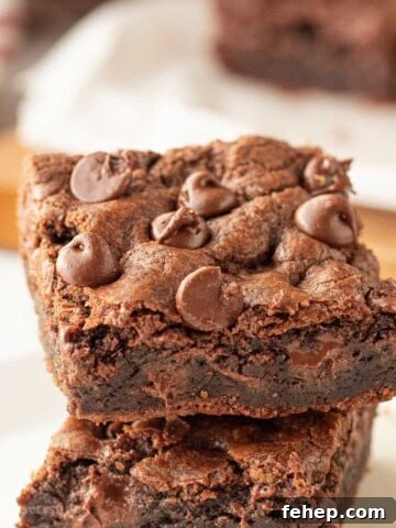 Stack of baked chocolate chocolate chip cookie bars on white plate.