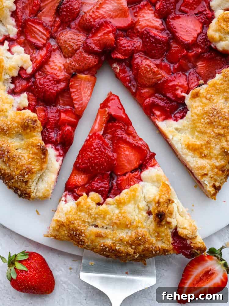 Close up and top view of a slice of galette being served. Fresh strawberries garnished on the side.