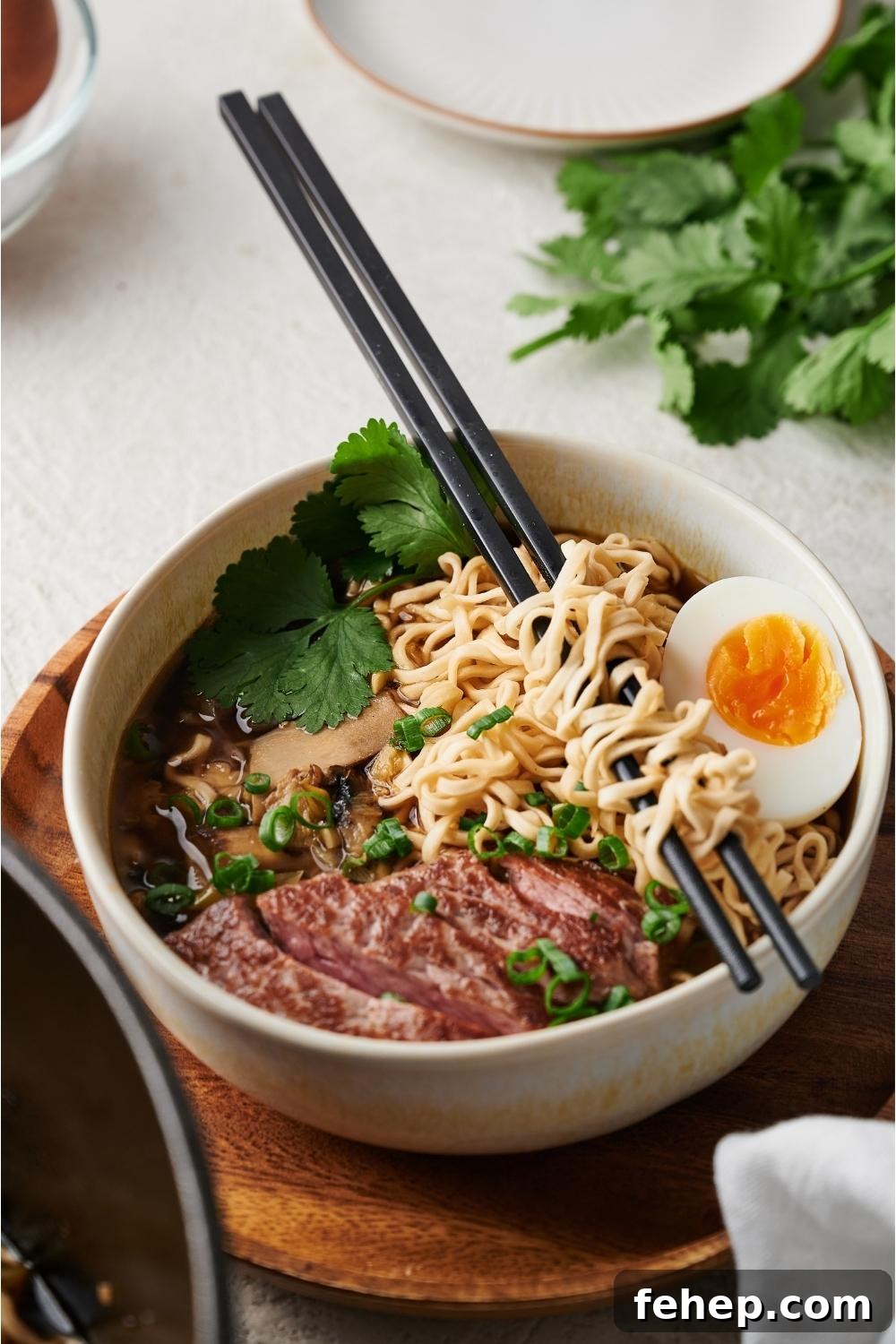 beef ramen in a white bowl on a wood plate with chopsticks resting on the bowl