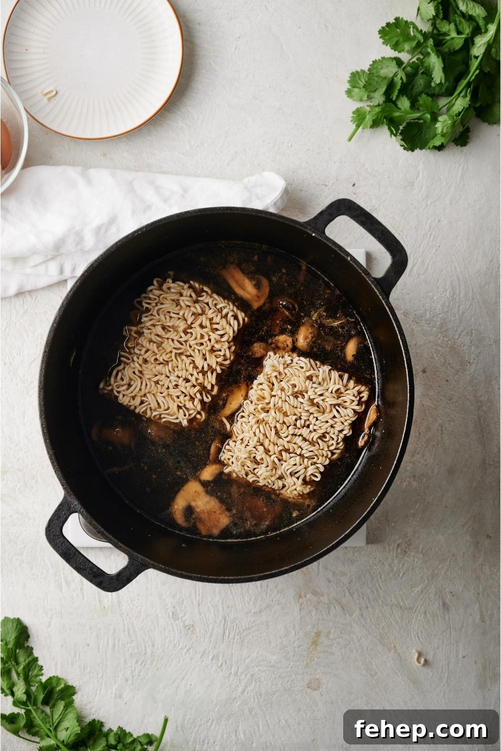 Dutch oven with beef broth ramen simmering and raw ramen noodles freshly added to the pan.