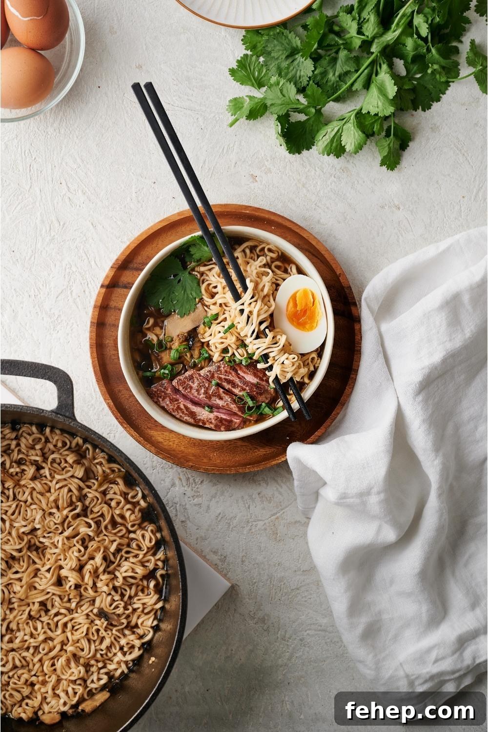 Beef ramen in a white bowl on a wood plate with chopsticks resting on the bowl and the rest of the ramen in a dutch oven next to the bowl