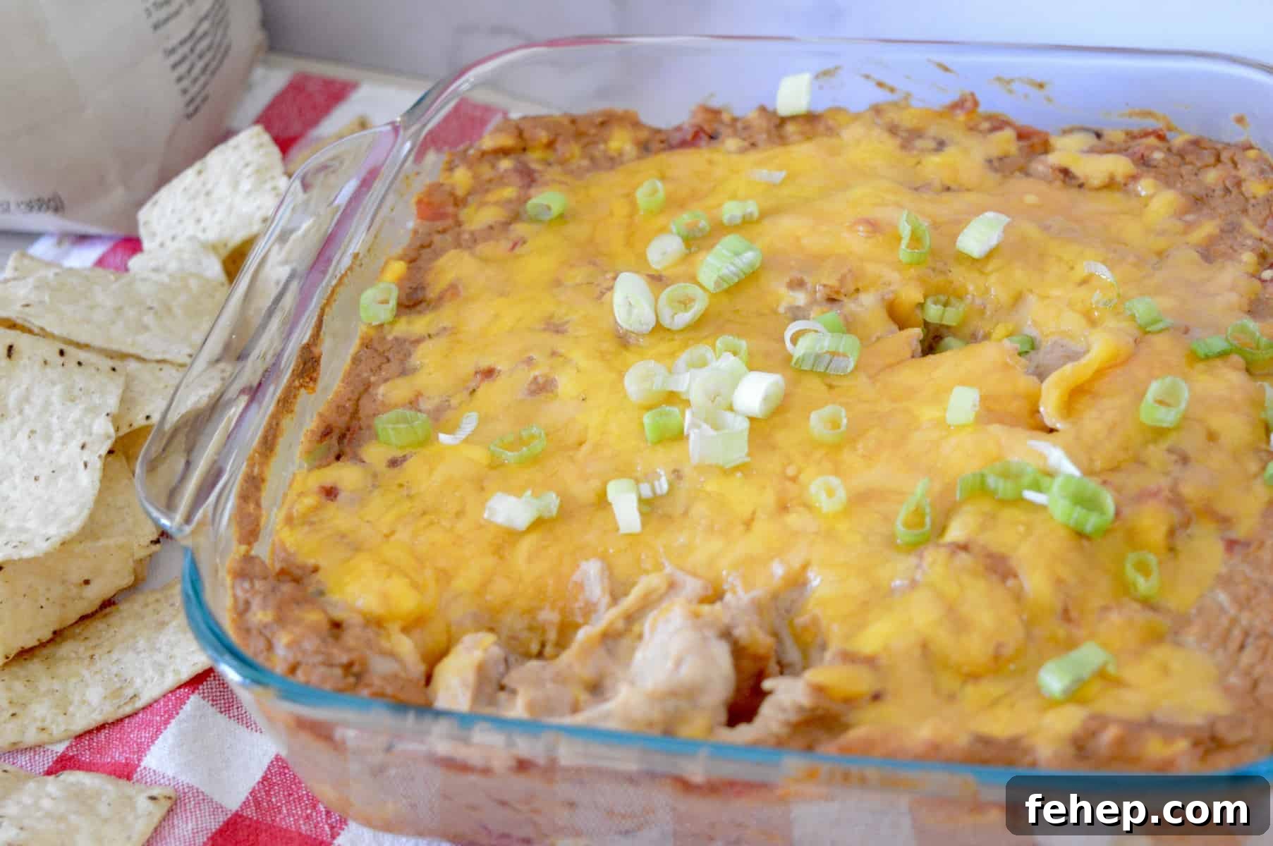 Cream Cheese Bean Dip in a glass pan with green onions on top.