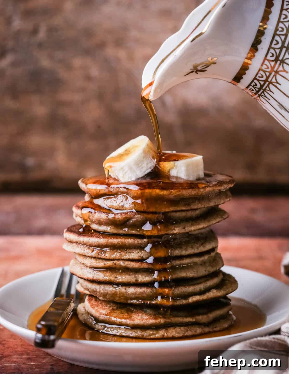 A stack of thick, soft and fluffy banana pancakes. Topped with bananas and drizzled with maple syrup.